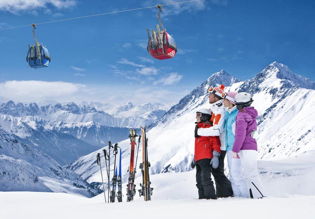 Family standing with skis looking at mountain range
